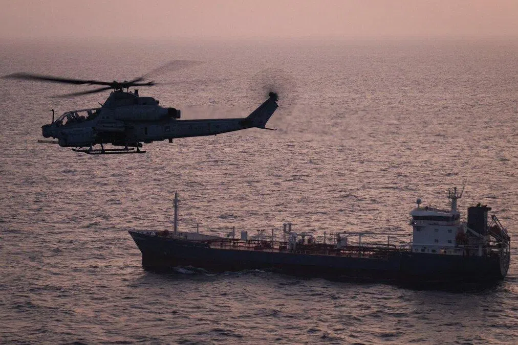 A US helicopter patrolling near a commercial vessel as American forces enforce the US' maritime blockade against Iran.
