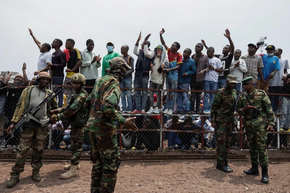 M23 rebels stand guard near civilians during a meeting organised by the M23 at the Stade de l'Unite, after the town of Goma was taken by the M23 rebels, in Goma, Democratic Republic of Congo, February 6, 2025. REUTERS/Arlette Bashizi