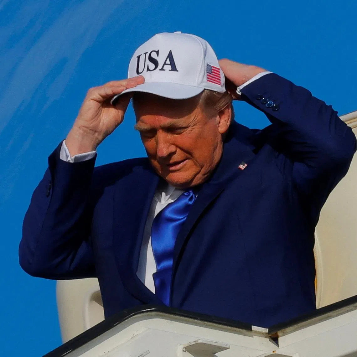 FILE PHOTO: U.S. President Donald Trump adjusts a hat as he disembarks Air Force One, as he arrives at Amsterdam Airport Schiphol in Schiphol, Netherlands, June 24, 2025. REUTERS/Brian Snyder/ File Photo