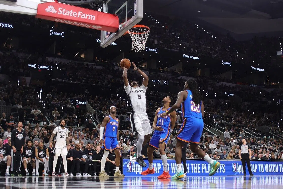 Stephon Castle of the San Antonio Spurs attempts a shot against Aaron Wiggins and Shai Gilgeous-Alexander of the Oklahoma City Thunder during the third quarter in Game 4.
