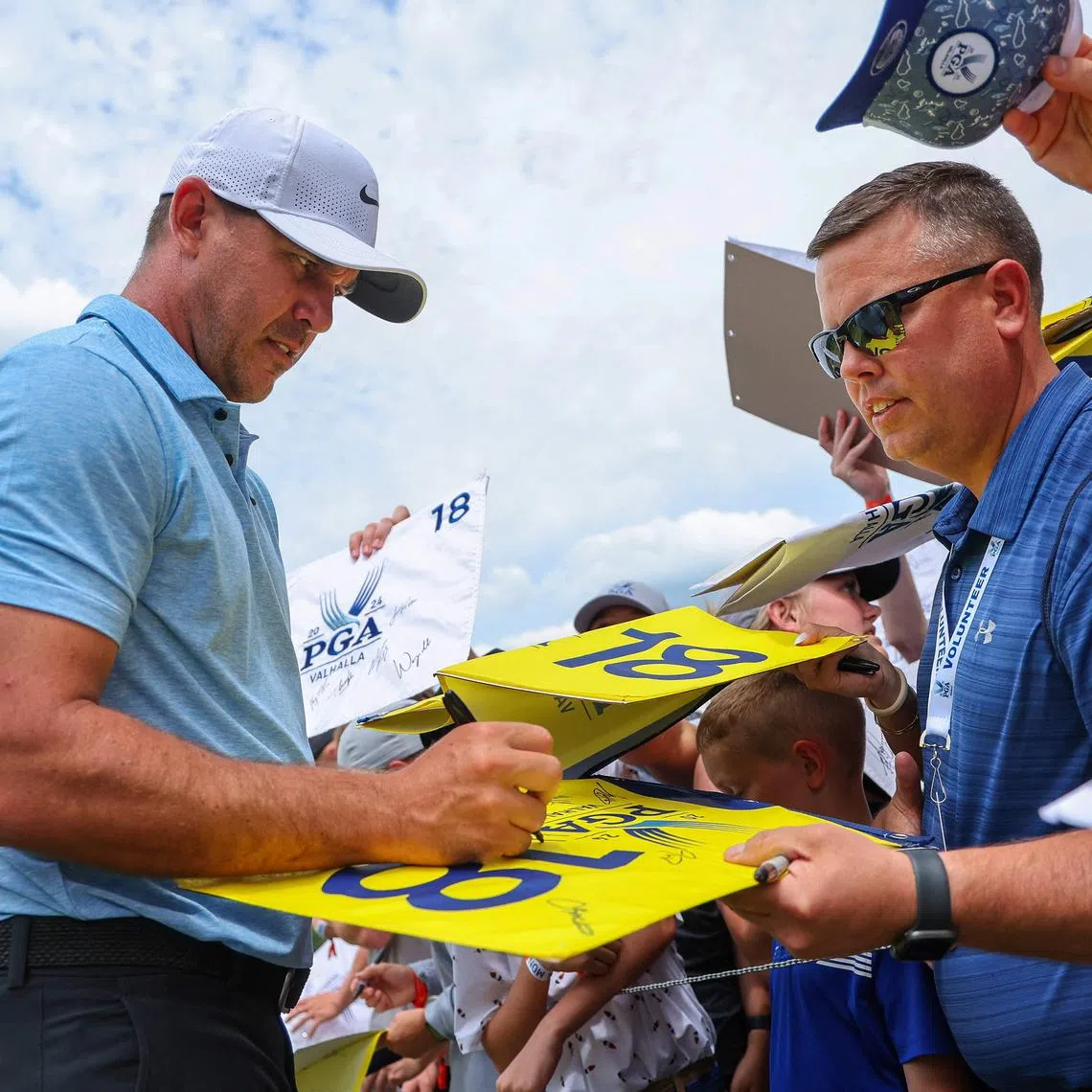 Brooks Koepka of the United States signs his autograph for fans during a practice round prior to the 2024 PGA Championship at Valhalla Golf Club.