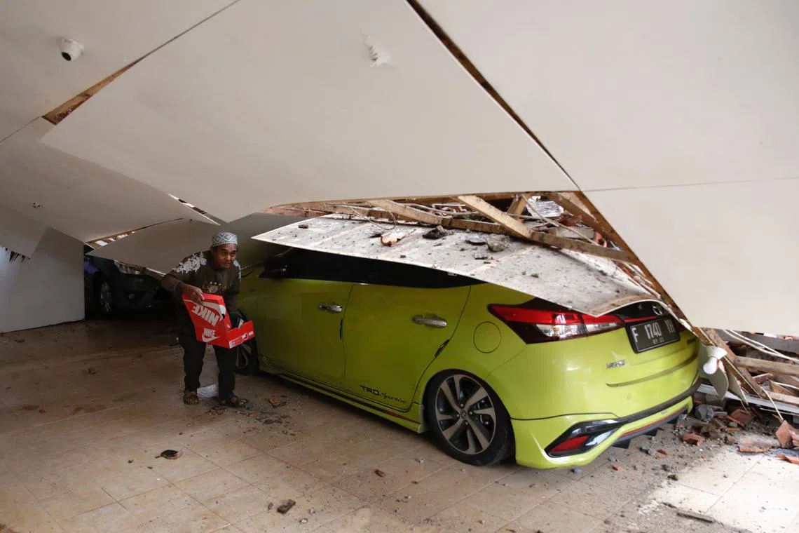 A man carries his belongings inside his damaged house after a 5.6 magnitude earthquake, in Cianjur, Indonesia, Nov 22, 2022. 