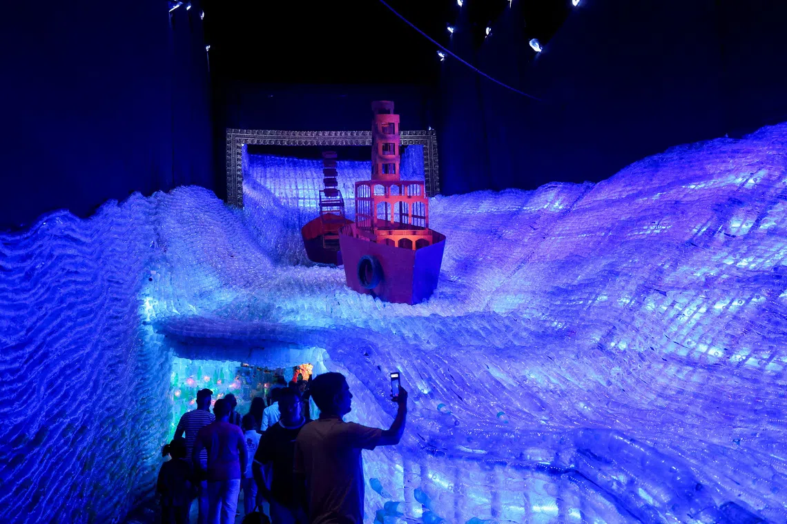 A man taking pictures at the entrance of a pandal made with plastic themed as a man-made aquarium highlighting the environmental crisis of plastic pollution and its impact on marine life, during Durga Puja celebrations in Kolkata, India on Oct 1, 2025. 