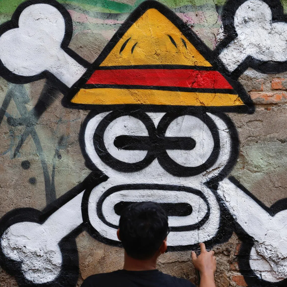 Artist Kemas Muhammad Firdaus, 28, spray-painting a Jolly Roger influenced by the popular Japanese series 'One Piece' in Bekasi. The symbol has been adopted in protest ahead of Indonesia's Independence Day on Aug 17.