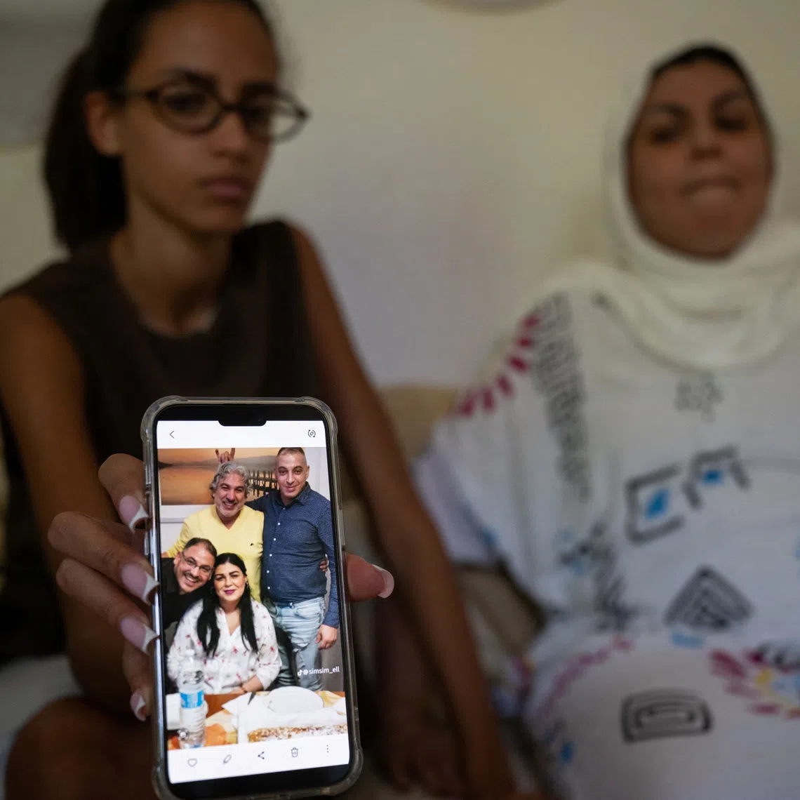Yossra, the niece of Abderrahim Fakir, holds a mobile phone displaying a family photograph that includes Fakir, as his sister Khadija sits beside Yossra, in Bologna, Italy, July 29, 2026. REUTERS/Michele Lapini