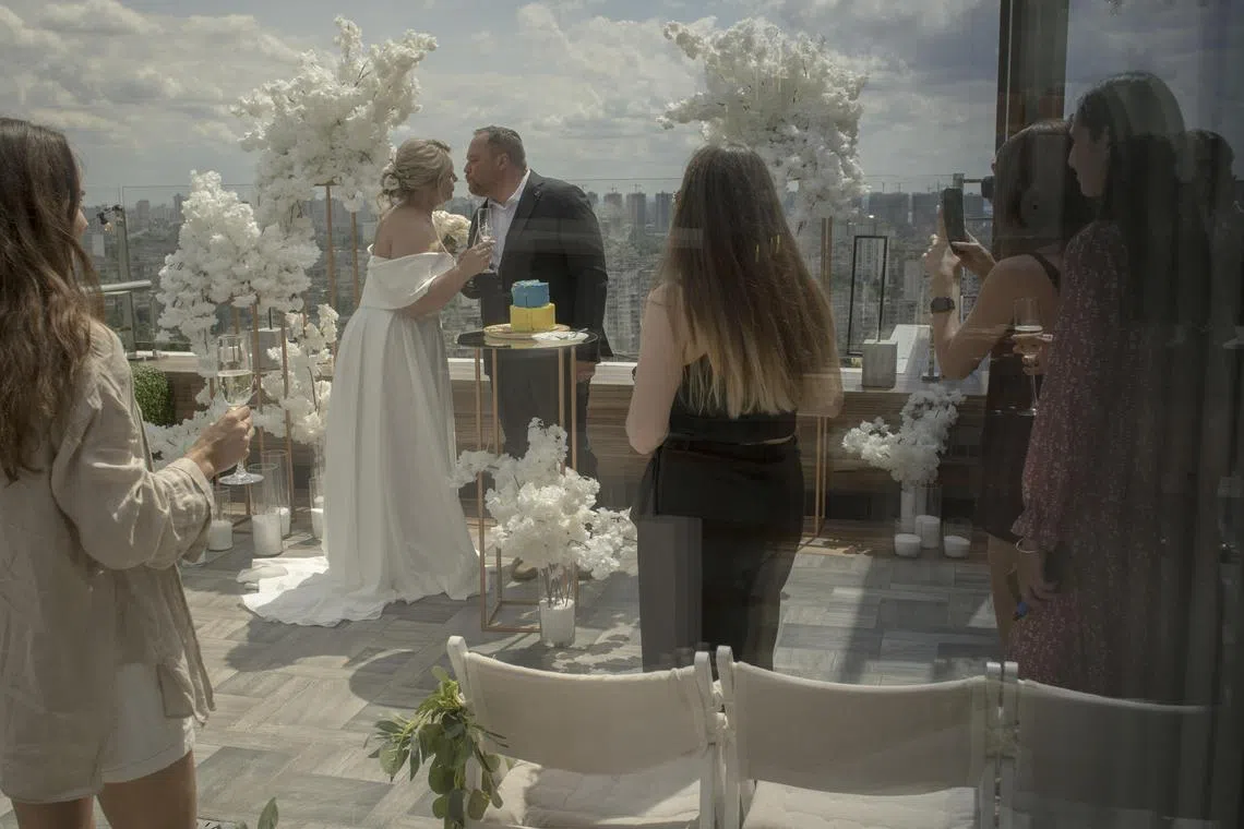 Yuliya Dluzhynska, a medic, and Maksym Merezhko, a Ukrainian soldier are wed on a rooftop in Kyiv on July 11, 2023. Zemliachky, a charity group that provides uniforms and other essentials to female soldiers, has pivoted to meet the growing demand for weddings for service couples like this one, who were to return to the frontlines after their honeymoon. (Laura Boushnak/The New York Times)
