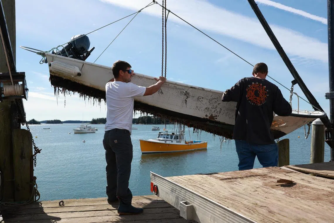 Mr Cameron O'Neal (right) helps Mr Brian Ciome pull his skiff out of the ocean, in Stonington, Maine, in preparation for Hurricane Lee's arrival.