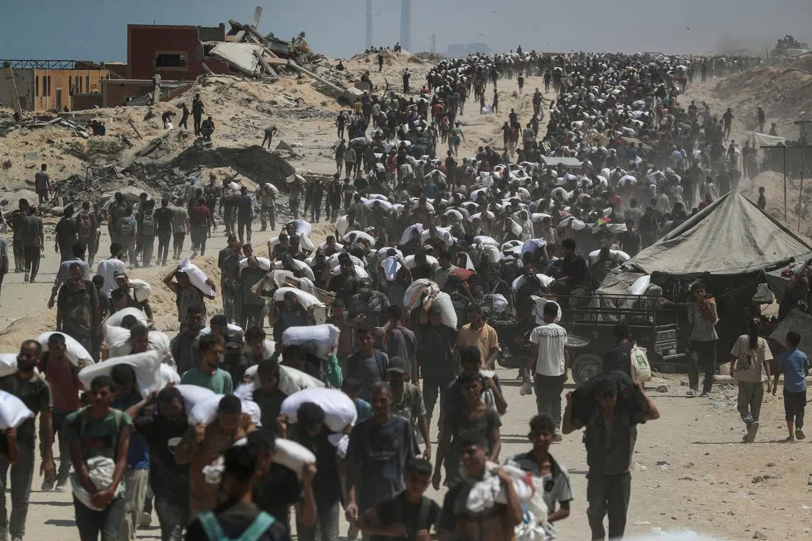 FILE PHOTO: Palestinians carry aid supplies that entered Gaza through Israel, in Beit Lahia, northern Gaza Strip, July 27, 2025. REUTERS/Mahmoud Issa/File Photo