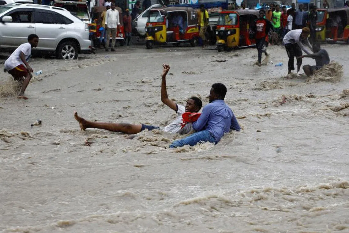 FILE PHOTO: A man attempts to rescue a boy from raging flood waters following heavy rains in Mogadishu, Somalia November 9, 2023. REUTERS/Feisal Omar/File Photo