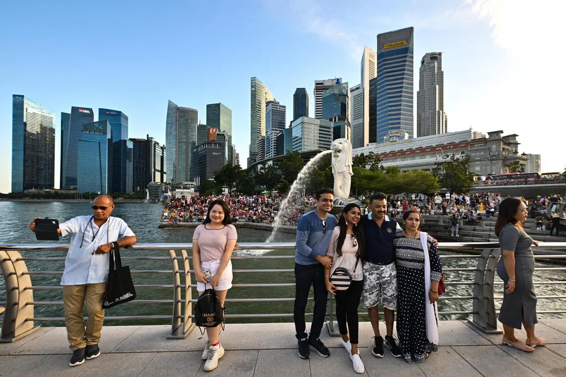 People taking photographs at Merlion Park against skyline of the Central Business District (CBD) and Marina Bay Financial Centre on July 16, 2022. 
