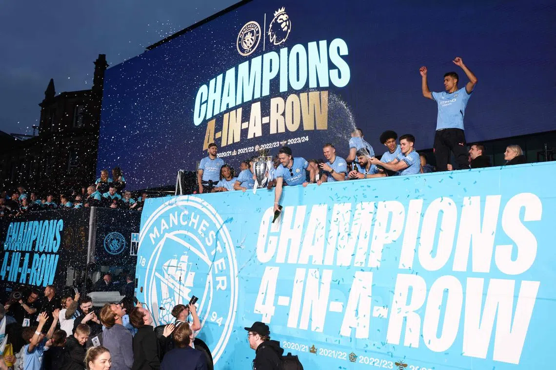 Manchester City players celebrate during an open-top bus victory parade for their Premier League title win.