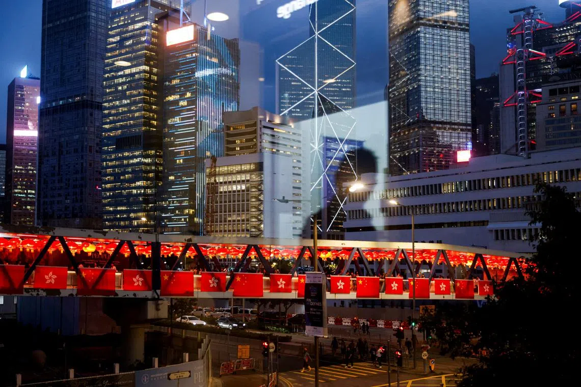 The reflection of a man is seen on the glass, while a pedestrian footbridge in the background is adorned with China's and Hong Kong's flags as decorations for the celebration of National Day, in Hong Kong, China October 3, 2023. REUTERS/Tyrone Siu/File photo