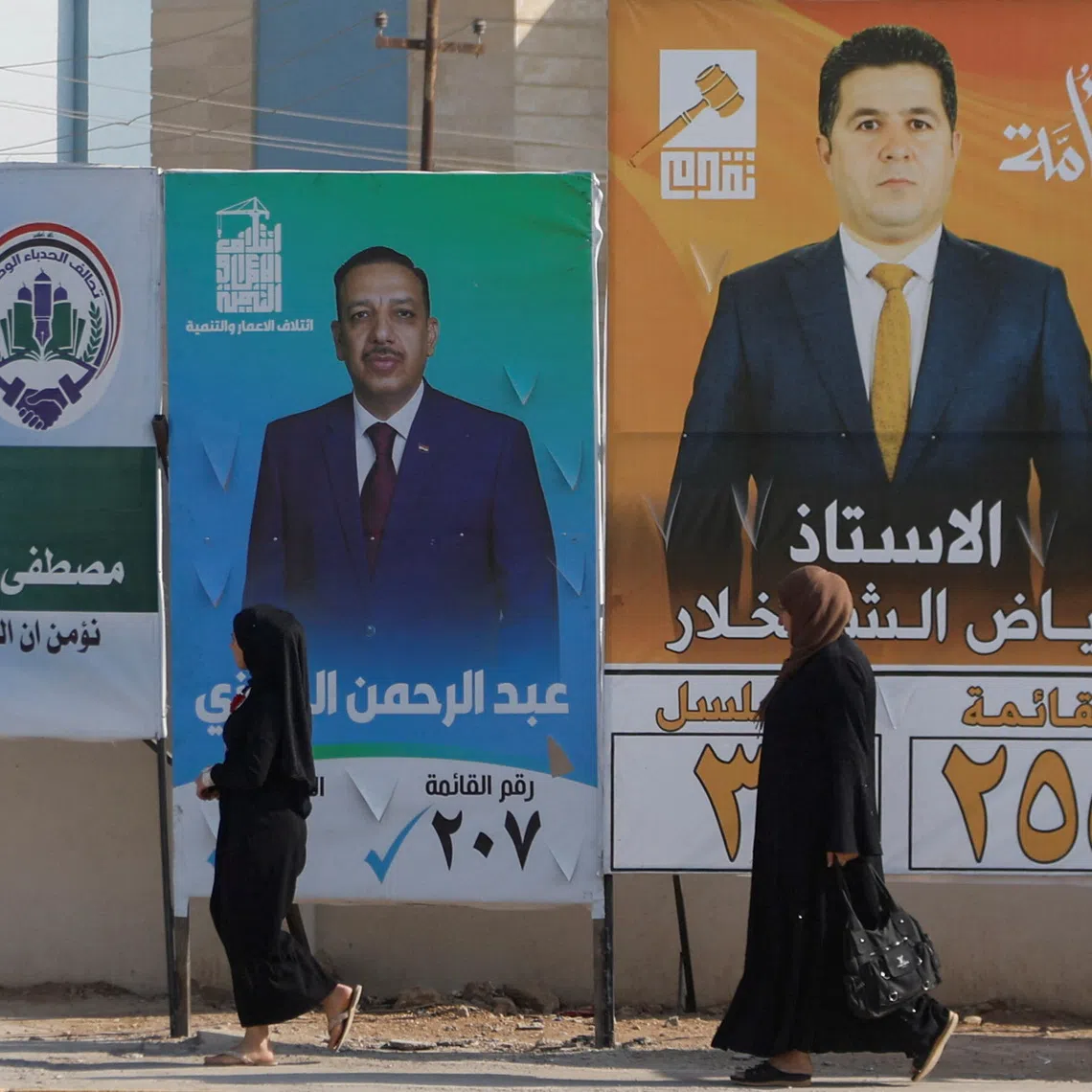 Women walk past campaign posters of candidates ahead of Iraq’s upcoming parliamentary elections in Mosul, Iraq, November 6, 2025. REUTERS/Khalid al-Mousily
