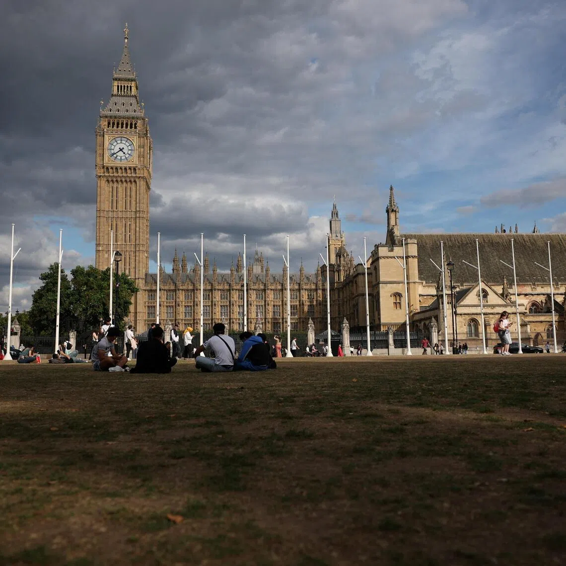 People sitting on dry grass at Parliament Square under an overcast sky in London on Sept 1. More than 80% of England is now in a state of drought.