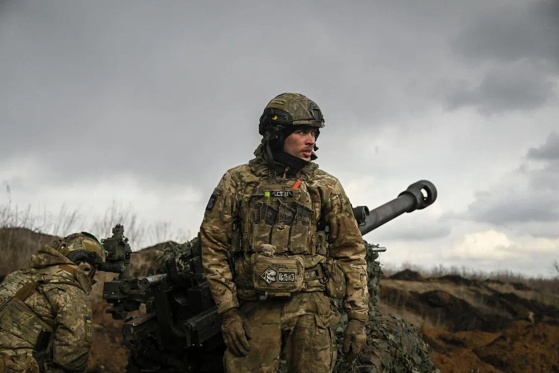 A Ukranian serviceman stands in front of a 105mm howitzer, near the city of Bakhmut, on March 8, 2023.