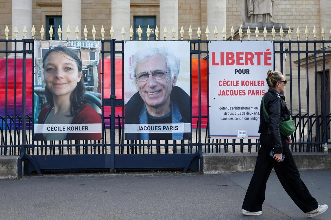 A woman walks past posters with the portraits of Cecile Kohler and Jacques Paris, two French citizens held in Iran, on the day of support rallies to mark their three-year detention and to demand their release, in front of the National Assembly in Paris, France, May 7, 2025.