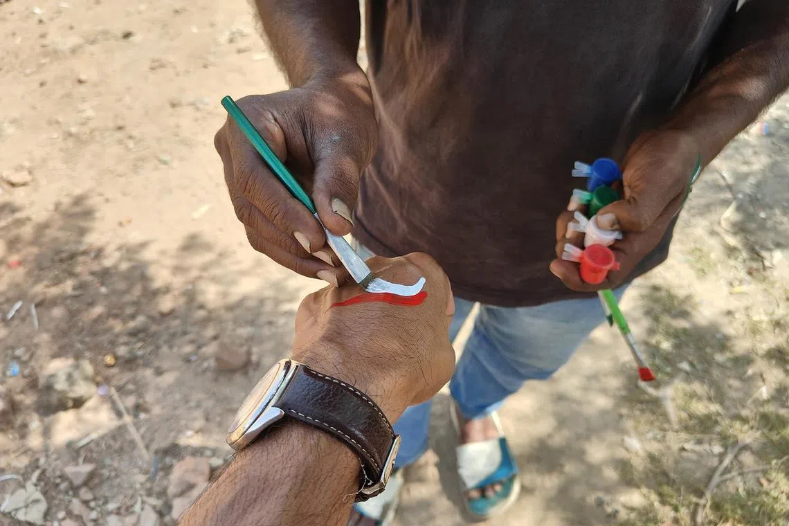 ddattari - Mr Rajinder Singh paints the Indian flag on my wrist, something he does to earn a living at Attari, a village on the Indo-Pak border that is famous among tourists for a daily border closing ceremony. 

ST PHOTO: DEBARSHI DASGUPTA