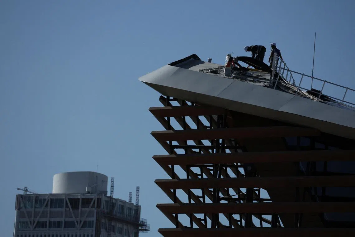 Workers working on the roof of the Paris Olympic Aquatics Centre, Saint-Denis, near Paris, France.
