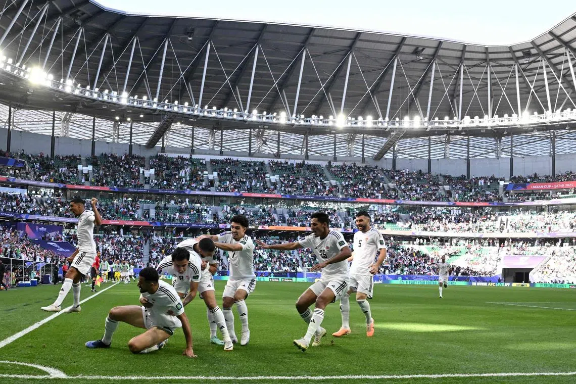 Iraq forward Aymen Hussein celebrates with teammates after scoring his team's first goal in the 2-1 Asian Cup win over Japan.
