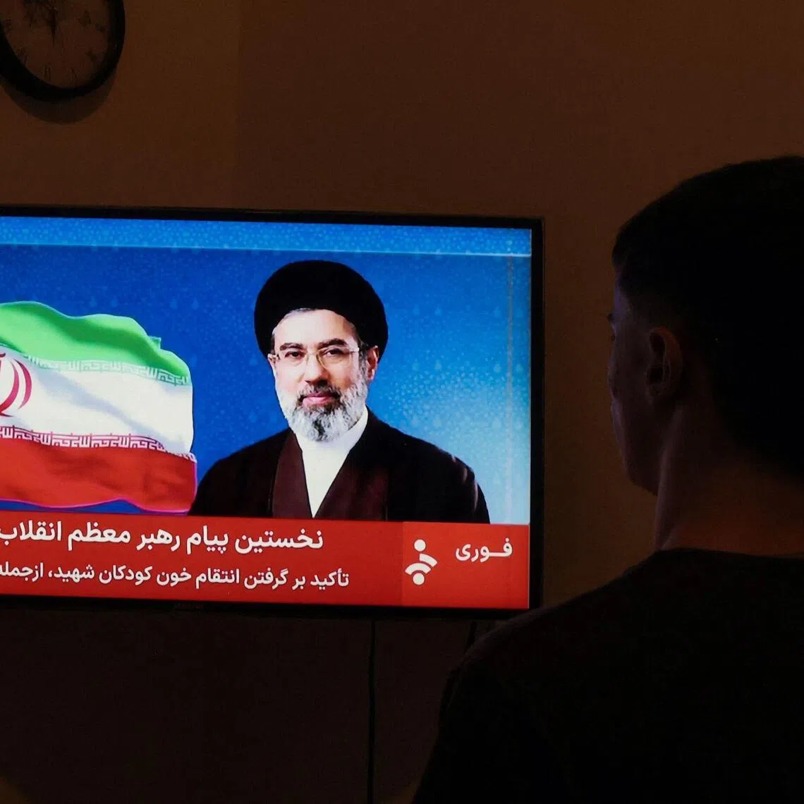 A man watches a televised statement by Iran's new supreme leader Mojtaba Khamenei on March 12, 2026. 