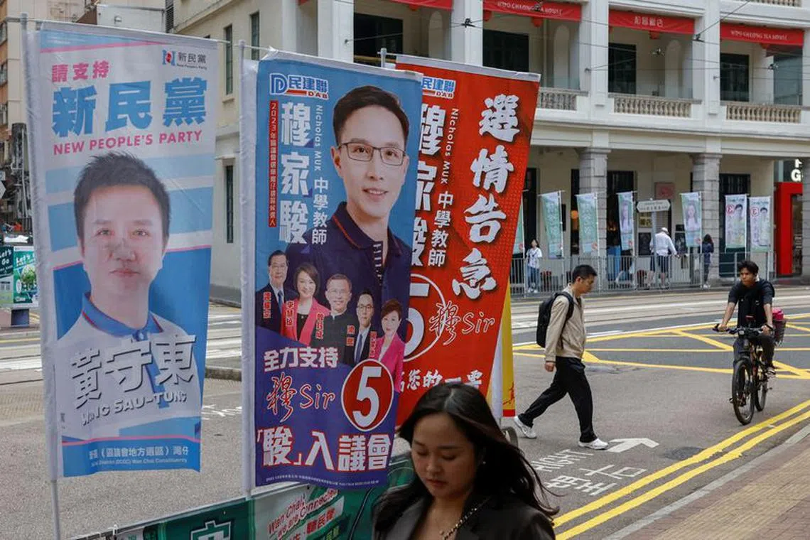 A woman walks past campaign banners of district council election candidates displayed on a street in Hong Kong, China December 9, 2023. REUTERS/Tyrone Siu