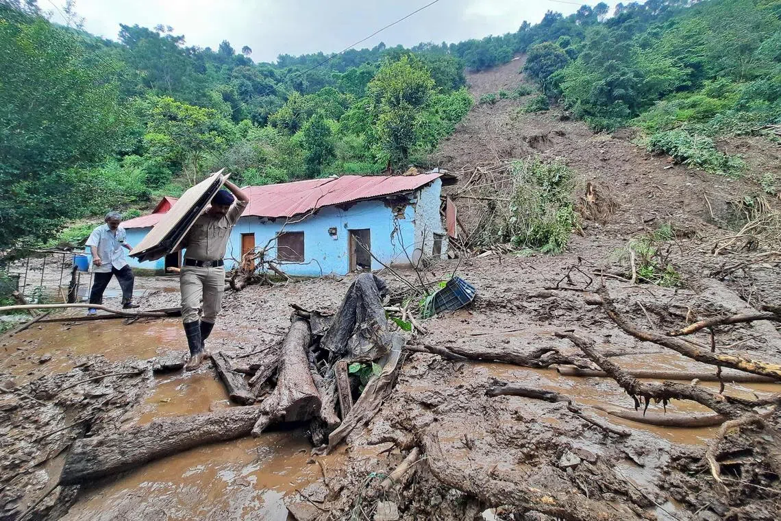 A security personnel carrying the belongings of a villager from the site of a landslide after heavy rains at Jadon village in Solan district of India's Himachal Pradesh state on Monday. 