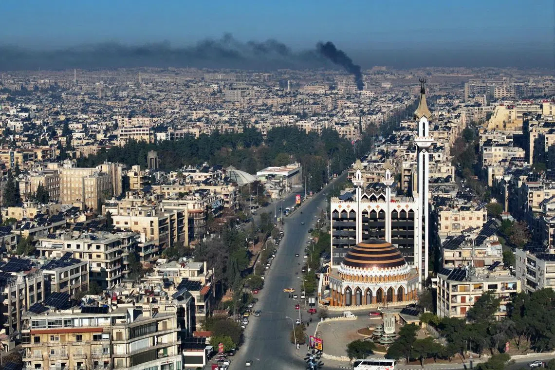 An aerial view shows a deserted street in Aleppo with smoke rising in the background after jihadists and their allies entered the northern Syrian city on Nov 30.