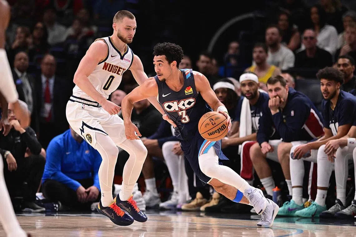 Jared McCain of the Oklahoma City Thunder handles the ball while being defended by Christian Braun of the Denver Nuggets during the first half at Paycom Center.