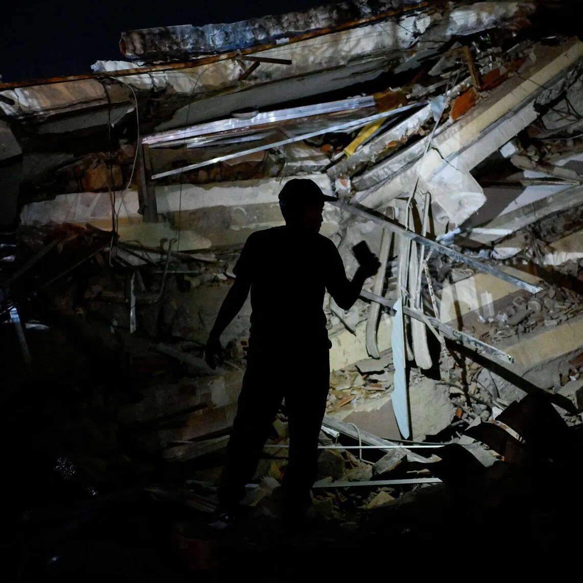 A person flashes a mobile phone at a destroyed building after an earthquake, in La Guaira, Venezuela, June 24, 2026. REUTERS/Maxwell Briceno