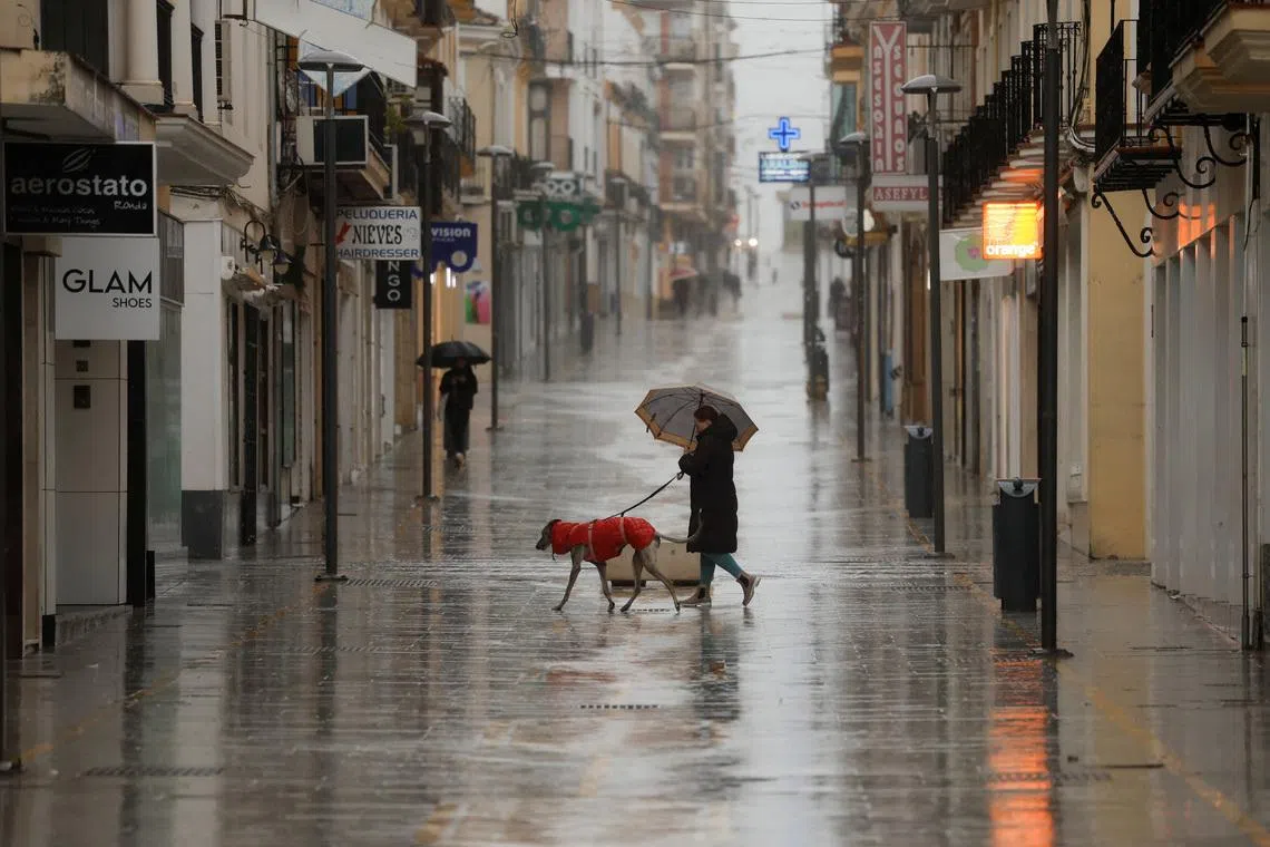 People walk in a shopping area amid rain as storm Leonardo hits parts of Spain, in Ronda, Spain, February 4, 2026. REUTERS/Jon Nazca