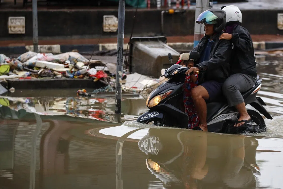 epa10503984 Motorcyclists ride through flood water in an alleyway after some areas in Johor state were affected by flooding, in Kota Tinggi, Johor state, Malaysia, 05 March 2023. According to state media, more than 44,000 people were evacuated to relief centers due to flooding. EPA-EFE/FAZRY ISMAIL