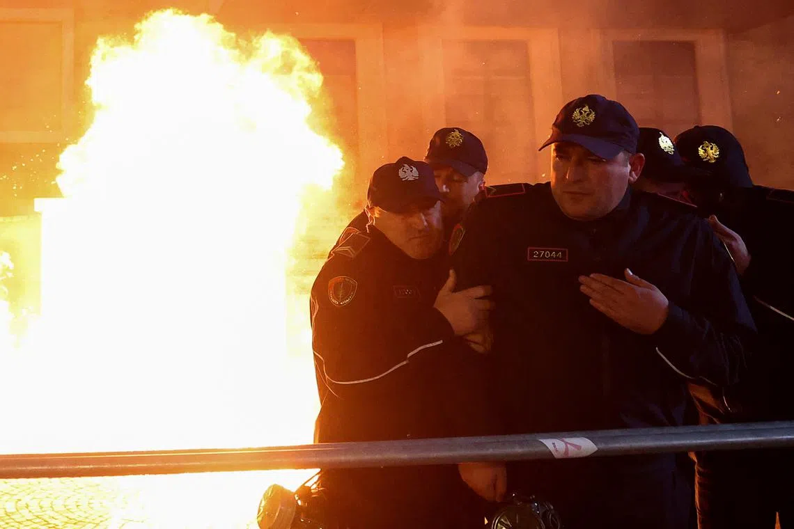 Police officers stand guard while a fire burns, as supporters of the opposition attend an anti-government protest in front of Prime Minister Edi Rama's office in Tirana, Albania, February 20, 2024. REUTERS/Florion Goga