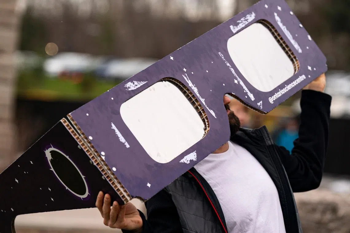 A visitor posing with oversized solar viewing glasses during an eclipse viewing event in Niagara Falls, Canada, on April 8, 2024. 
