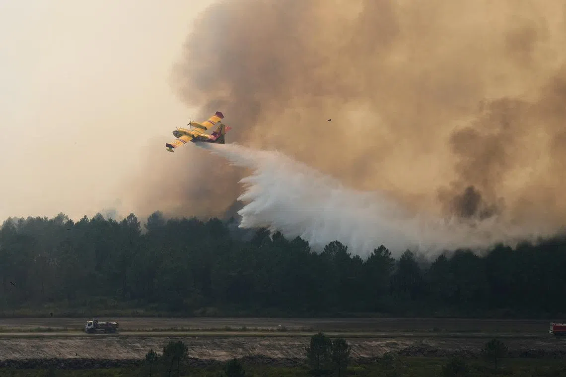 A plane drops water on a fire near Ares, during wildfires in the area of southwestern France, Tuesday, July 28, 2026. Baz Ratner/Pool via REUTERS