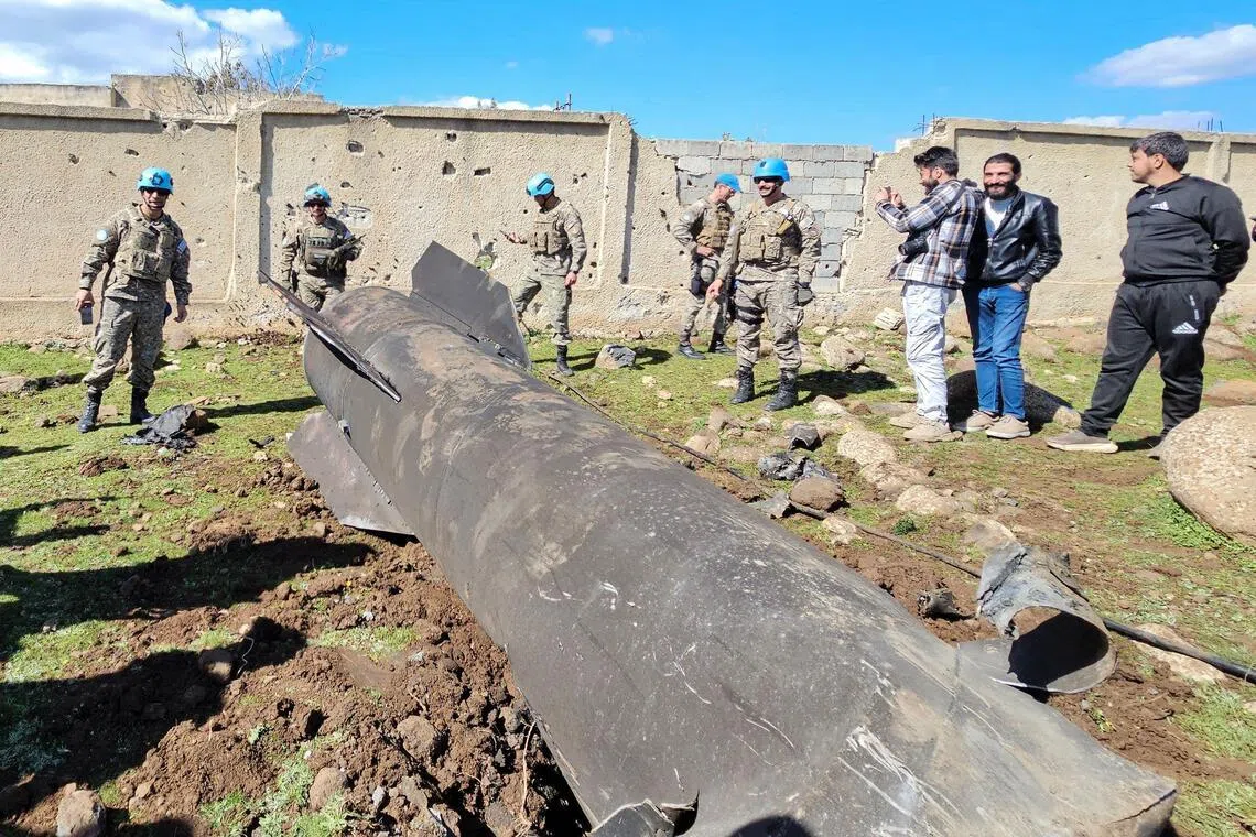 United Nations peacekeepers and civilians standing near the wreckage of an Iranian rocket that was reportedly intercepted by Israeli forces, in the southern Syrian countryside of Quneitra, near the Golan Heights, close to the town of Ghadir al-Bustan. 