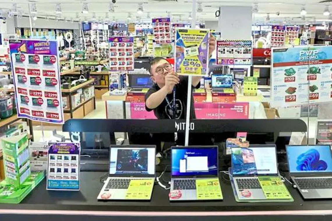Worker adjusting 'sale' signs at an electronics shop in Komtar, Penang. 