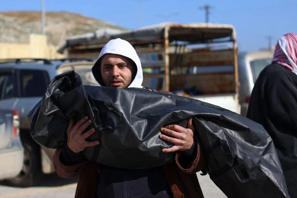 A Syrian man carries away the body of a relative killed in an earthquake in Turkey's Hatay region, upon its arrival in Syria via the border crossing of Bab el-Hawa, on Feb 8, 2023.