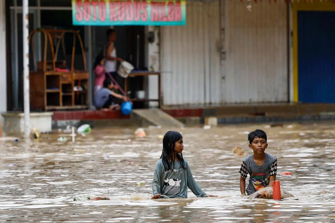 Children wading through water in a flooded residential area following heavy rains in Bekasi, on the outskirts of Jakarta, on March 4. 