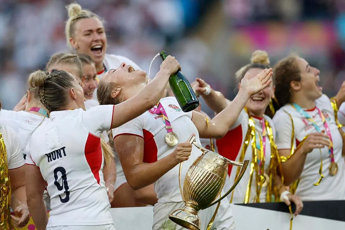 England's Zoe Aldcroft holds the women's rugby World Cup trophy as she celebrates with Natasha Hunt.