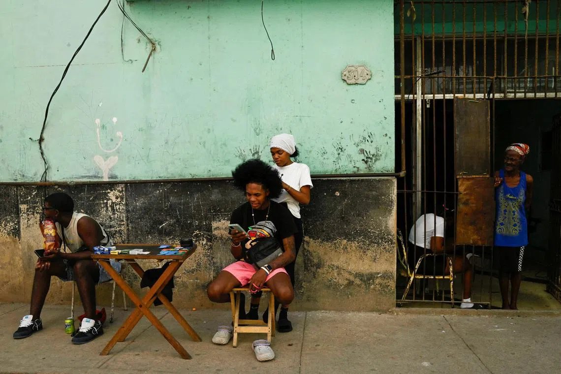 A boy having his hair combed by his friend on a sidewalk, in Havana, Cuba, on Jan 11, 2026.