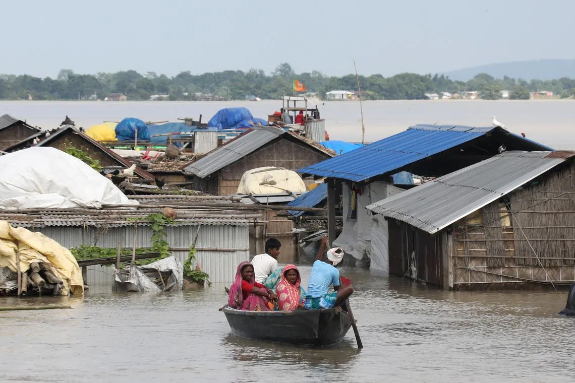 A flood affected family rows a boat near their submerged house during floods in Katahguri village, in Assam, India.