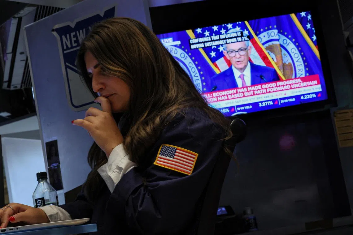 A trader works on the floor of the New York Stock Exchange, as a screen displays a news conference by Federal Reserve Board chairman Jerome Powell, following the Fed rate announcement.