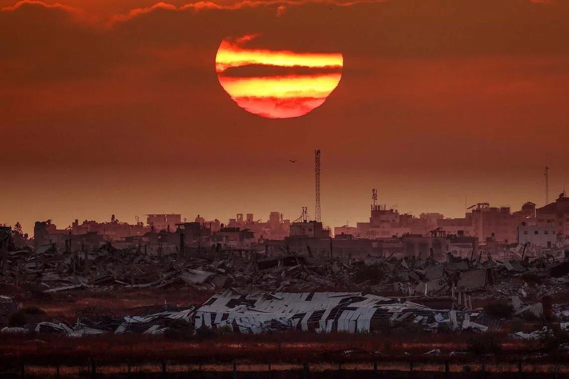 This picture taken from a position on the Israeli border with the Gaza Strip, shows the sun setting behind destroyed buildings in the besieged Palestinian territory on June 10.