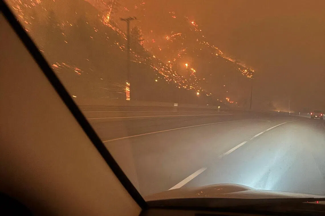 The hillside burns as residents evacuate towards Kelowna on Aug 8.