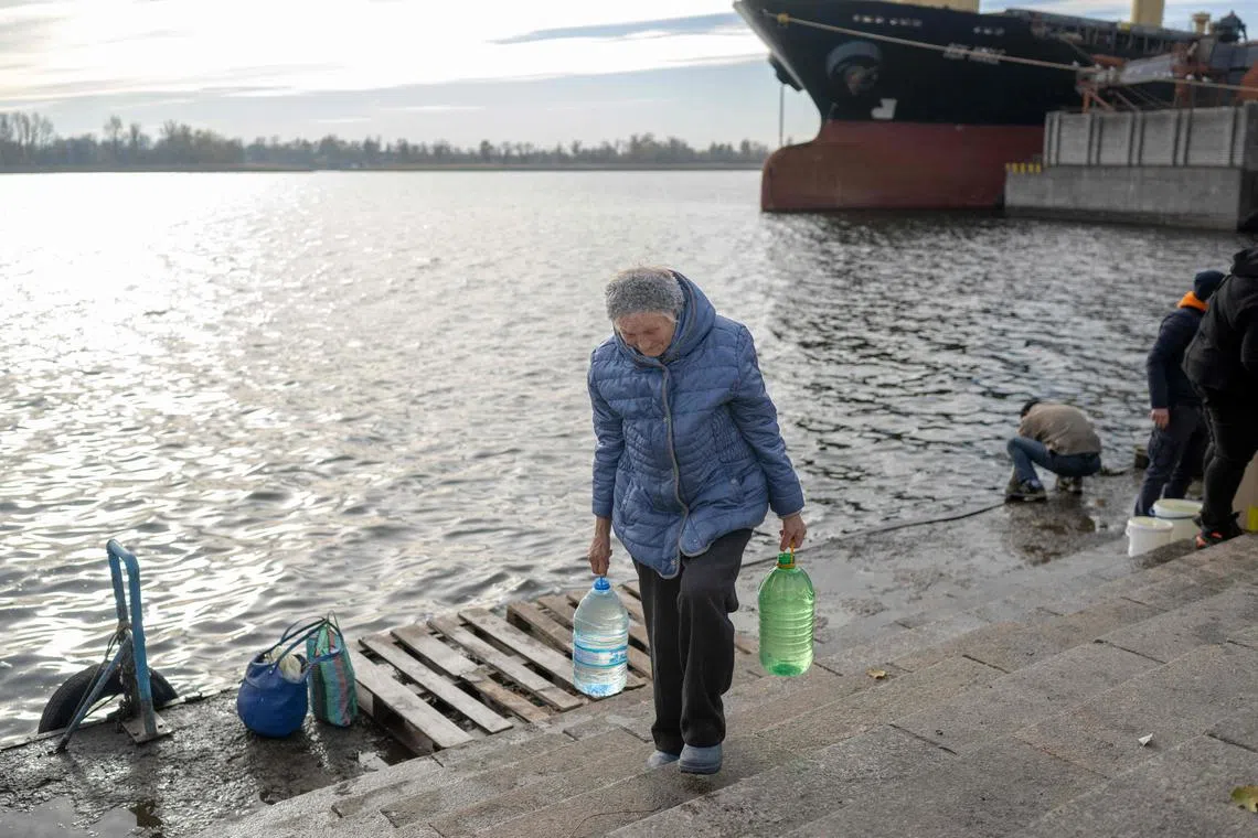 TOPSHOT - Woman carries bottles with the water from the Dnipro river in Kherson, on November 14, 2022, amid Russia's invasion of Ukraine. - The takeover by Ukrainian troops of the Kherson region is the latest in a string of setbacks for Russia, which invaded Ukraine on February 24 hoping for a lightning takeover and to topple the government in days. (Photo by BULENT KILIC / AFP)