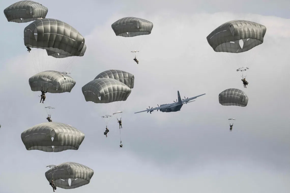 TOPSHOT - US Army paratroopers with the 3-509th Battalion, 11th Airborne division, jump out of a USAF C-130J Super Hercules during Operation Orient Shield 26 Joint Airborne drop at Kita-Dalen Training area in Eniwa, Hokkaido on September 15, 2026. (Photo by ANDREW CABALLERO-REYNOLDS / AFP)