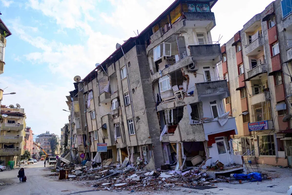 A local resident walks past a destroyed building in Hatay, Turkey, on Feb 11, 2023.