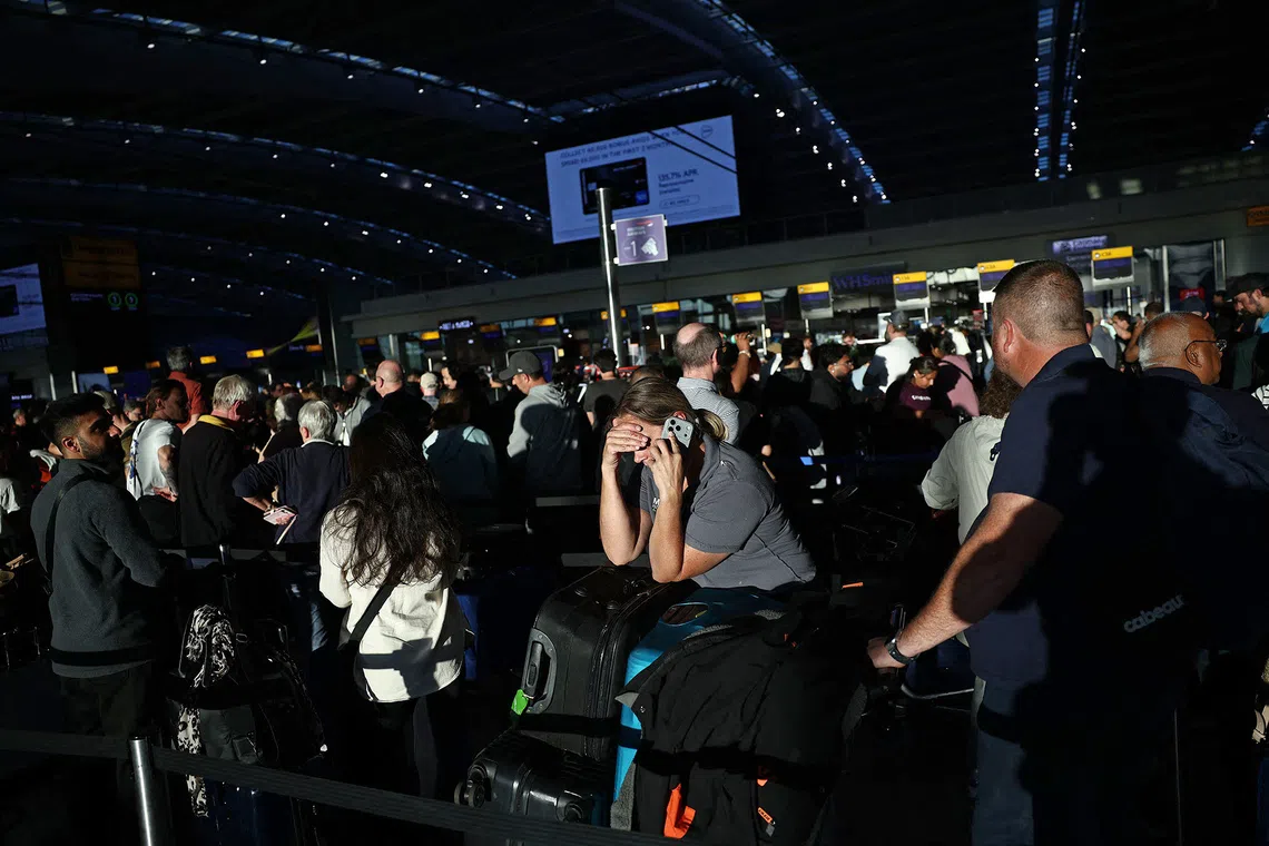 People stand with their luggage as the queue at check-in desks inside Terminal 5 of London Heathrow airport, west of London on September 8, 2026, following major disruption due an issue affecting the NATS air traffic control systems. More than 400 flights to and from UK airports were cancelled on September 8 due to what the country's air traffic control service said was a "technical issue", in the latest glitch to cause disruption. (Photo by Henry NICHOLLS / AFP)