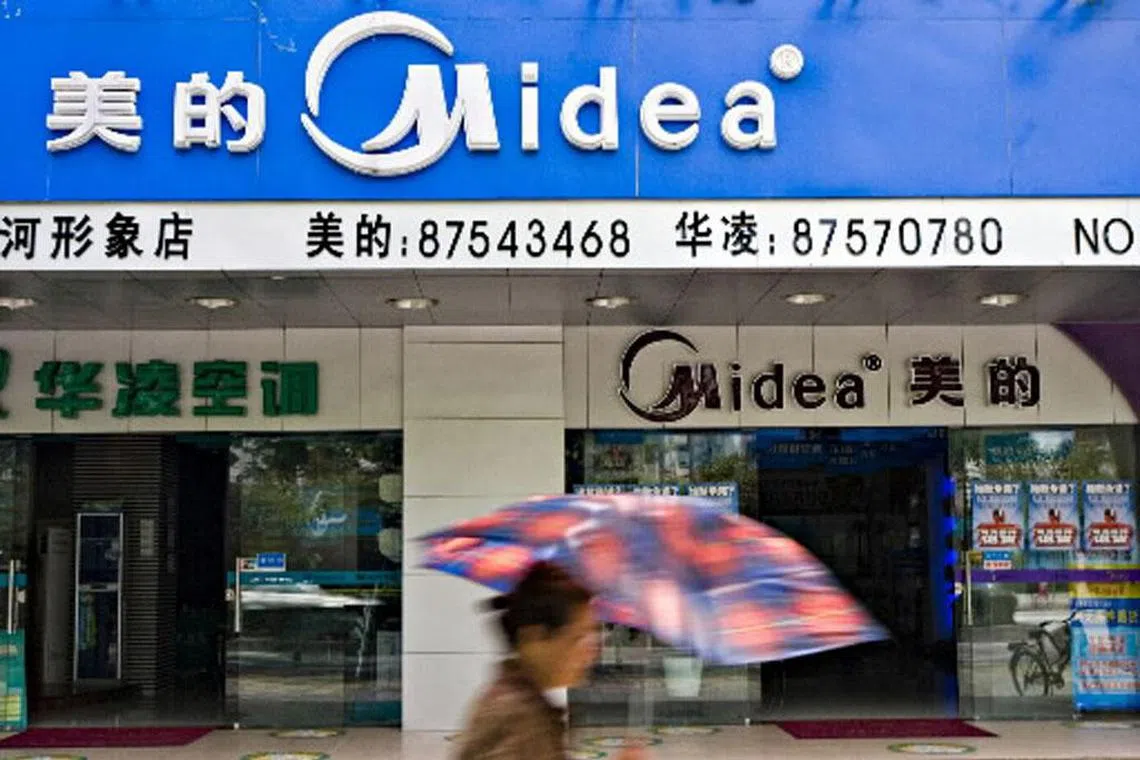 A woman shields herself from the sun while walking past a Guangdong Midea Electric Appliances Co. store, in Guangzhou, China, on Friday, June 15, 2007. Goldman Sachs Group Inc., the world's biggest securities firm, has been approved to buy 10.7 percent of Guangdong Midea Electric Appliances Co., China's second-biggest publicly traded appliance maker, according to a statement. Photographer: Michael Lassman/Bloomberg News