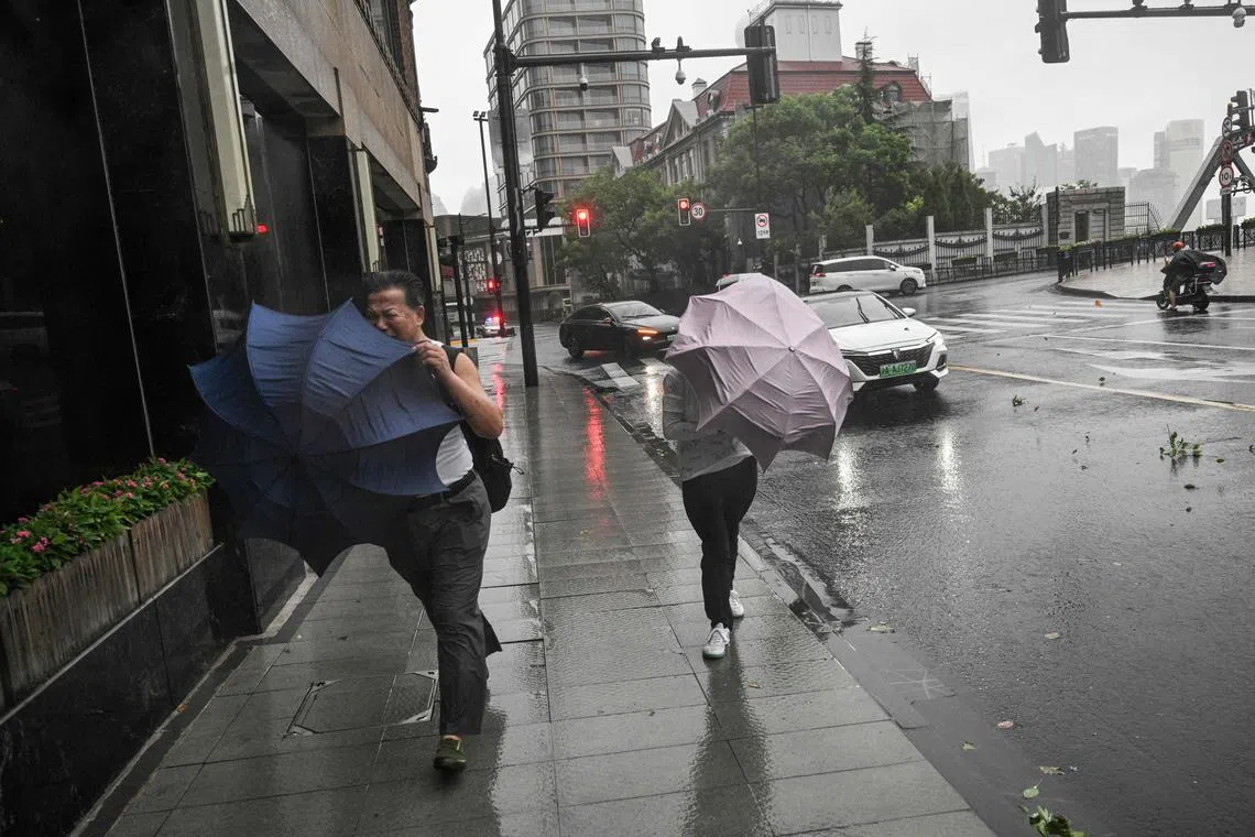 Pedestrians struggle with their umbrellas in strong winds and rain from the passage of Typhoon Bebinca in Shanghai on Sept 16.